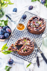 Delicious sweet pies with plums on white table, close-up