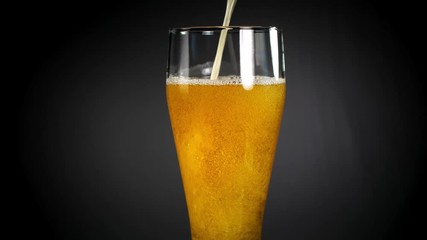 Cold light beer in a glass over black background. Craft beer close up. 4K UHD video