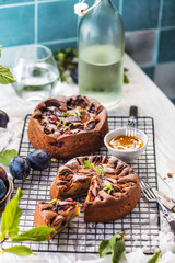 Delicious sweet pies with plums on white table, close-up