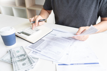 Man using calculator and calculate bills receipt in home expenses payments costs with paper note, financial account management and payment or saving concept.