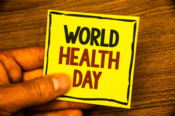 Word writing text World Health Day. Business concept for Special Date for Healthy Activities Care Prevention Man holding yellow paper ideas black red letters frame wooden background