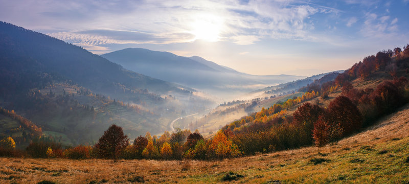 view from a mountain top in to the foggy valley. beautiful autumn landscape. forested hills in fall colors. sunrise with an amazing cloudscape. panorama of a synevyr national park district