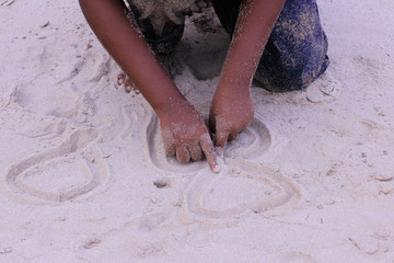 drawing heart on sand by during summer vacation