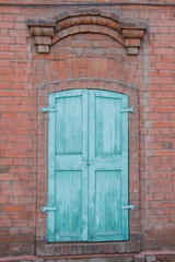 Fototapeta na wymiar Old closed wooden shutters on window of red brick house.