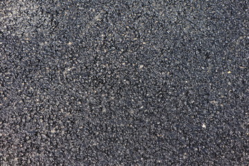 Texture of a rough tar surface of a new asphalt road in closeup, copy space