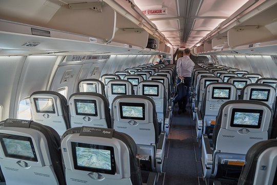 COPENHAGEN, DENMARK - MAY 8, 2018: Icelandair flight from Reykjavik to Copenhagen. Boeing 757 cabin interior after people got off the plane upon arrival. Glow of the infotainment screens.