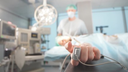 Male Patient prepared by a team of anesthetists for abdominal surgery, unconscious with drop counter in arm. Intensive Therapy