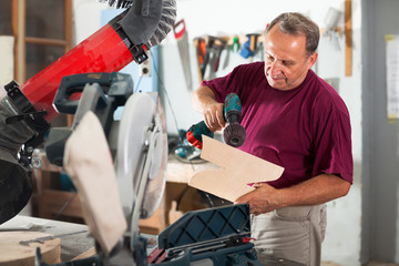 Worker grinds wooden 3d detail on grinding machine