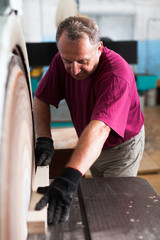 Carpenter handles wooden block on grinding machine