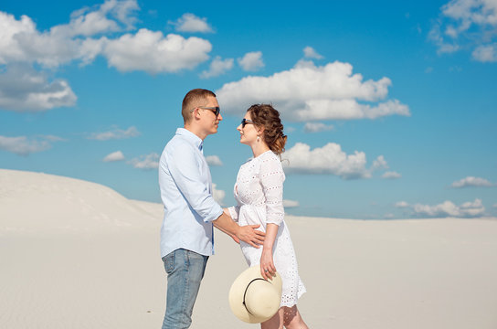 Young couple enjoying the sunset in the dunes. Romantic traveler walks in the desert. Adventure travel lifestyle concept.