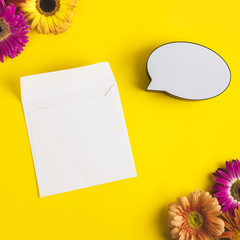 Bright beautiful gerbera flowers and paper card, bubble speech on sunny yellow background. Mother's Day, Valentine holiday. Place for text, lettering or product. View from above, Copy space. Flatlay.