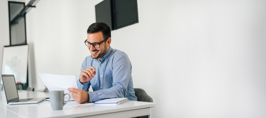 Young smiling cheerful confident businessman checking working plan and schedule or timetable in...