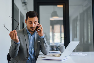 Stressed out businessman in office making important phone call about serious problem working under...