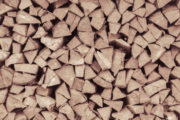 Wooden toned texture. Wall of dry chopped firewood logs in a pile. Summer harvesting for the winter.