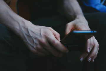Obraz premium Man pointing on smartphone screen, chatting in social networks. Close up of male hands and a smartphone.