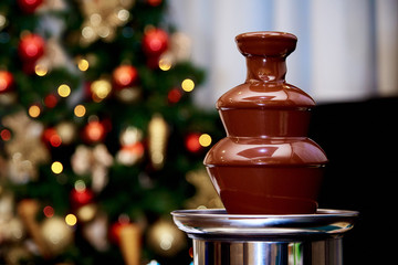 Hot chocolate fountain on the background of the Christmas tree.