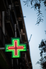 Pharmacy sign illuminated at night on spanish architecture facade
