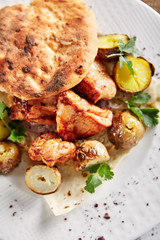 Grilled Pork with Potato, Spices and Pita Bread on Rustic Background Top View. Restaurant Main Course with Barbecue Meat, Vegetables, Flatbread Lavash or Pitta, Coriander, Black Pepper, Rosemary