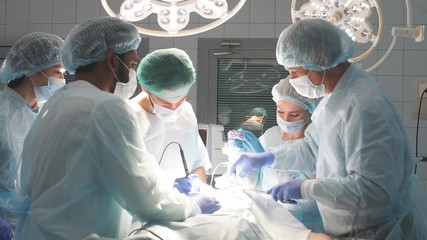 Group of practicing surgeons and medical practitioner observe the skillful actions of a famous surgeon.