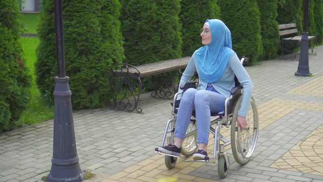 Young arab woman disabled with glasses and traditional scarf in a wheelchair