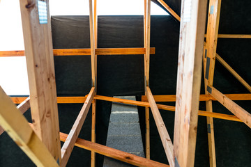 Fototapeta na wymiar Roof trusses covered with a membrane on a detached house under construction, visible roof elements, battens, counter battens, rafters.