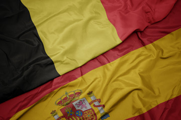 waving colorful flag of spain and national flag of belgium.
