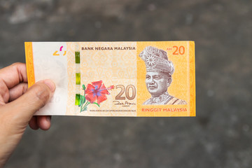 Twenty Ringgit Malaysia bank note on hand isolated on grey background.