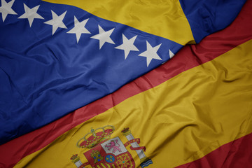 waving colorful flag of spain and national flag of bosnia and herzegovina.
