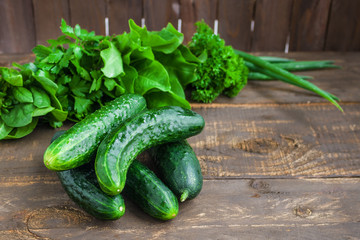 fresh harvesting cucumbers and herbs parsley spinach green onions on wooden table