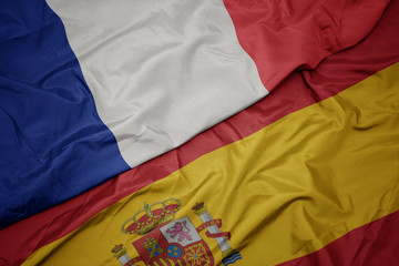 waving colorful flag of spain and national flag of france.