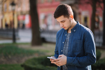 Young man use phone and wireless headphones and print message in social network