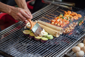 Street Cafe, North Vietnam. A man prepares seafood sticks, grilled rice in a cane on the grill