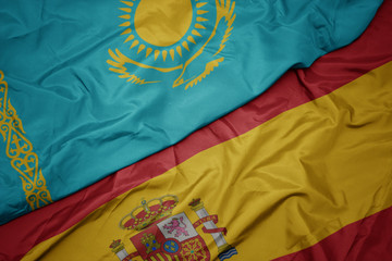 waving colorful flag of spain and national flag of kazakhstan.