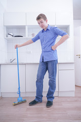 Teenager Boy Mopping The Floor and helps his parents to clean on kitchen