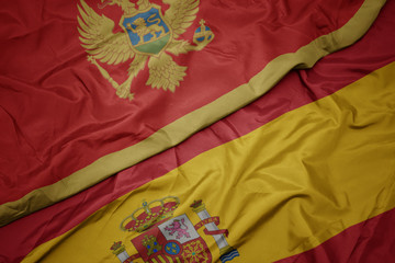 waving colorful flag of spain and national flag of montenegro.