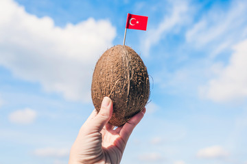Tropical coconut with Turkish flag in the form of a toothpick in female hands. Tourism in Turkey....