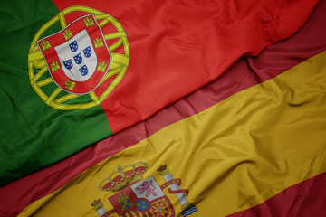 waving colorful flag of spain and national flag of portugal.