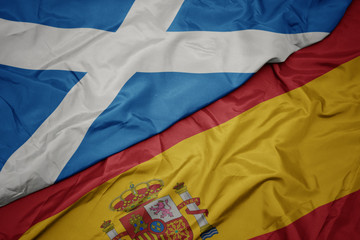 waving colorful flag of spain and national flag of scotland.