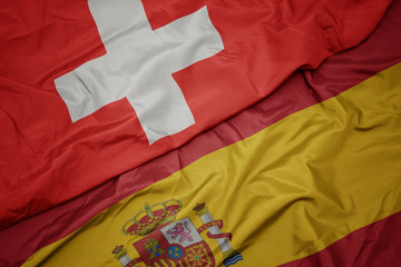 waving colorful flag of spain and national flag of switzerland.