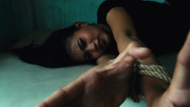 Detainee get suffering. She asking for helping and untie the rope. Poor woman is homeless and girl was procured by human trafficking and hidden her at the dark and dirty room in building. slow motion 