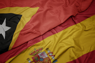 waving colorful flag of spain and national flag of east timor.