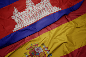 waving colorful flag of spain and national flag of cambodia.