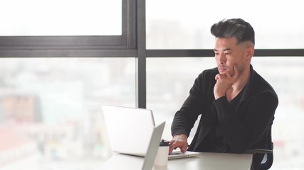 Portrait of a Chinese businessman sitting at the office table in the evening.