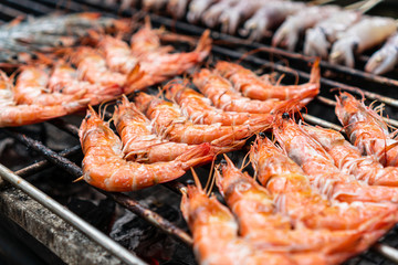 Grilled shrimps on stick on the flaming grill. Street seafood.