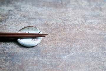 Wooden chopsticks and chopstick rest on rustic background. Close up. Copy space. 