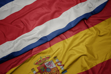 waving colorful flag of spain and national flag of costa rica.