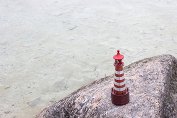 A toy lighthouse stands on a stone. View from above.