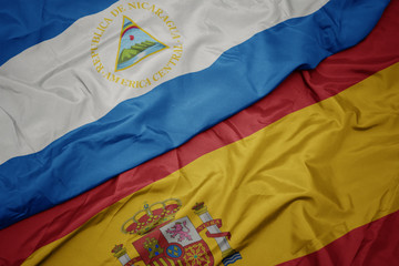 waving colorful flag of spain and national flag of nicaragua.