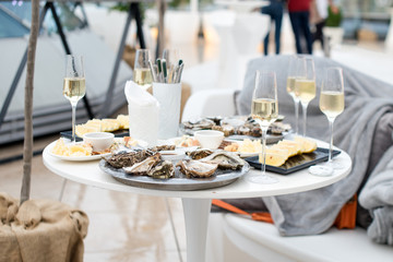Opened oysters and lemon with white wine on the table. Restaurant delicacy, beautiful table setting. Saltwater oysters dish. Romantic dinner in restaurant.