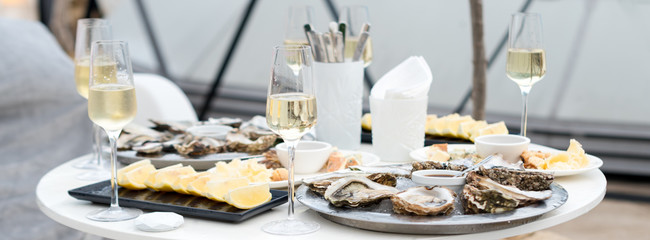 Opened oysters and lemon with white wine on the table. Restaurant delicacy, beautiful table...